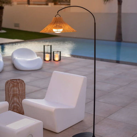 Lámpara de pie LED Niza con batería para exteriores IP54 con pantalla de fibra natural junto a la piscina en un área exterior moderna.