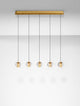 Licio Pendelleuchte Balken 84cm 5-flammig 3000K Gold in einem modernen Wohnraum, mit goldenem Aluminium und transparentem Acryl.