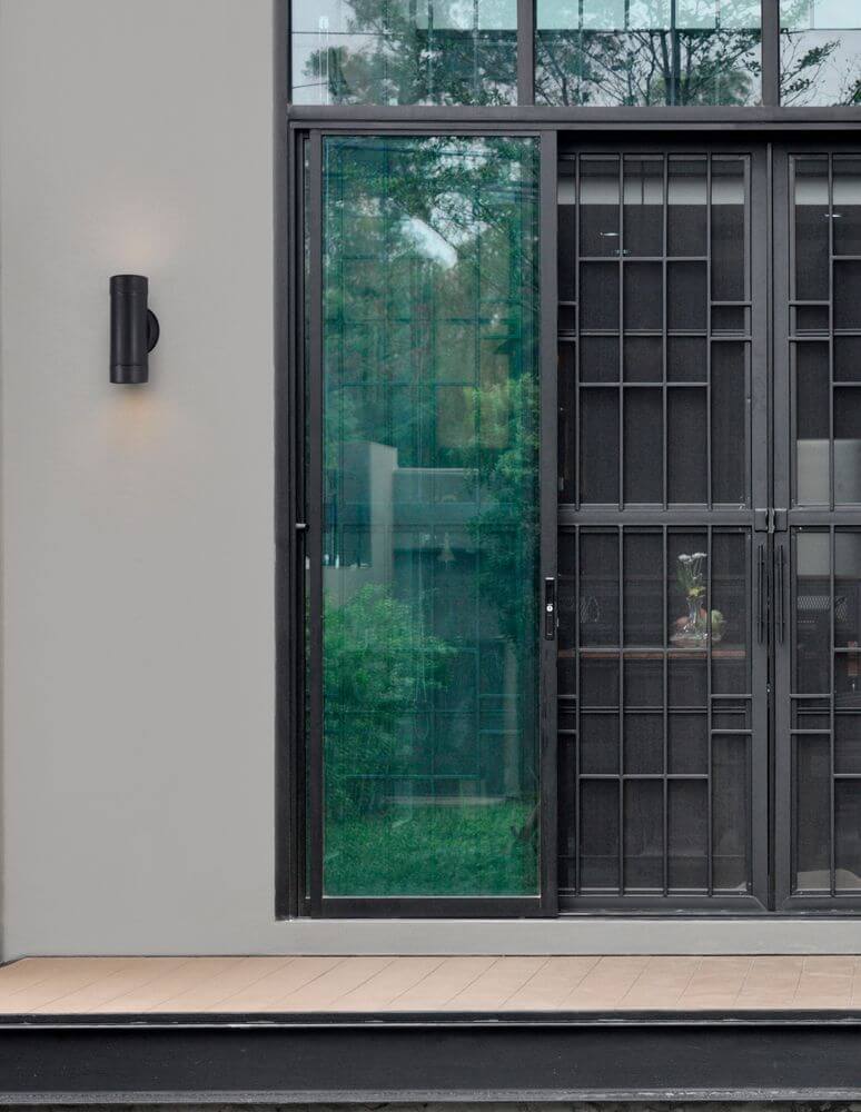 Limbio Außenwandleuchte H 18cm GU10 Up & Down IP54 an einer modernen Hauswand mit Glas und Holzterrasse.