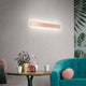 Antille LED-Wandleuchte Large in modernem Design, angebracht an einer Wand über einem stilvollen Tisch.