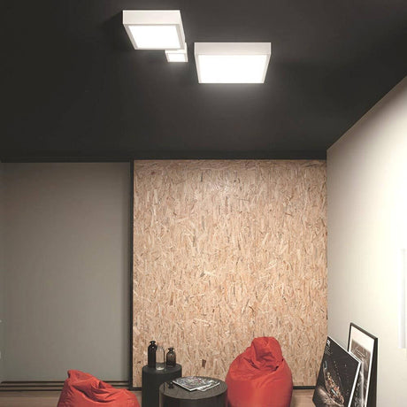 Box SQ LED-Deckenleuchte Large in modernem Raum mit bunten Sesseln und Holzwand.