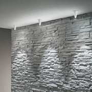 Conus X LED plafonnier sur un mur en pierre moderne, éclairage décoratif en intérieur.