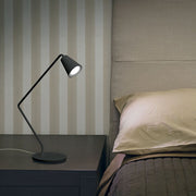 Conus tab LED-Tischleuchte 2W auf einem Nachttisch neben einem Bett mit gestreifter Wand.