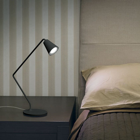 Conus tab LED table lamp 2W on a bedside table next to a bed with a striped wall.