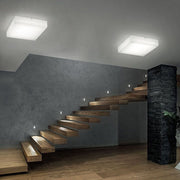 Gluèd SQ LED-Deckenleuchte in modernem Treppenhaus mit Holzstufen und eleganten Lichtakzenten.