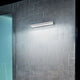 Halfpipe M LED-Wandleuchte an einer stilvollen Wand mit Fliesen beleuchtet den Raum.