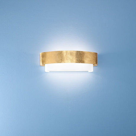 Matrioska W Wandleuchte Big an einer blauen Wand, kombiniert goldene und weiße Elemente.