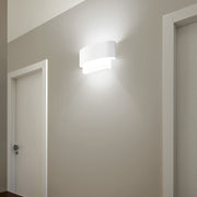 Matrioska W Wandleuchte Mini an einer Wand mit zwei Türen, modernes Design und sanfte Beleuchtung.