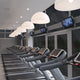 Moderner Fitnessraum mit Laufbändern und stylischen Pendelleuchten für optimale Beleuchtung.