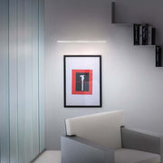 Straight W LED-Wandleuchte Large über einem modernen Kunstwerk in einem stilvollen Raum.