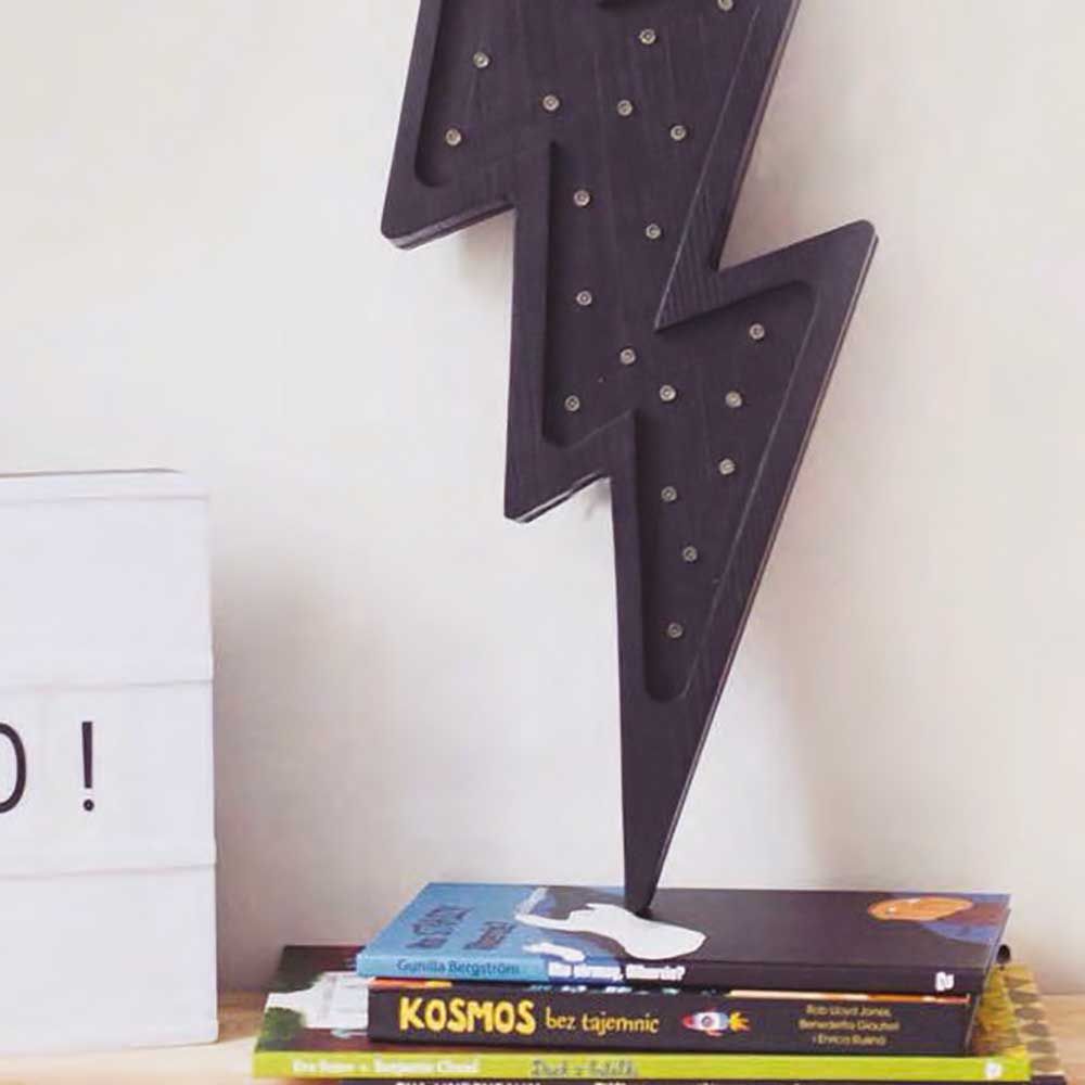 Holzlampe in Blitzform mit Dimmer, auf einem Bücherstapel platziert, ideal für Kinderzimmer.