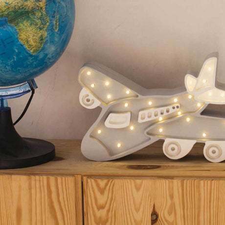 Kinder-Wandleuchte Flugzeug auf einer Holzkommode neben einem Globus, mit warmem Licht und Dimmer-Funktion.