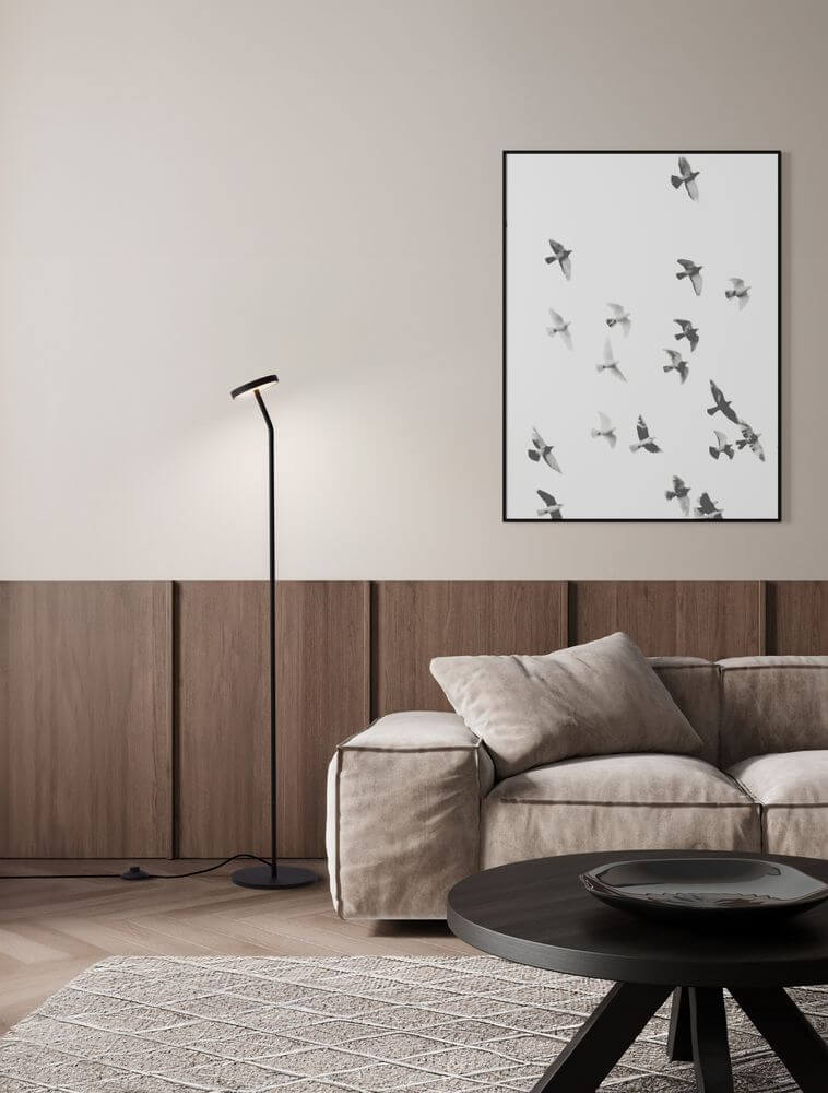 Moderne Einrichtung mit der Logos Stehlampe 3000K Schwarz neben einem gemütlichen Sofa und Kunstwerk an der Wand.