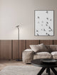 Moderne Einrichtung mit der Logos Stehlampe 3000K Schwarz neben einem gemütlichen Sofa und Kunstwerk an der Wand.