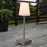 Petite lampe de terrasse Lucca avec base en béton massif gris sur une terrasse en bois, design moderne avec abat-jour diffusant la lumière.