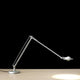 Luceplan Berenice Schreibtischlampe mit flexiblem Arm und 360° drehbarem Leuchtkopf auf Tisch.