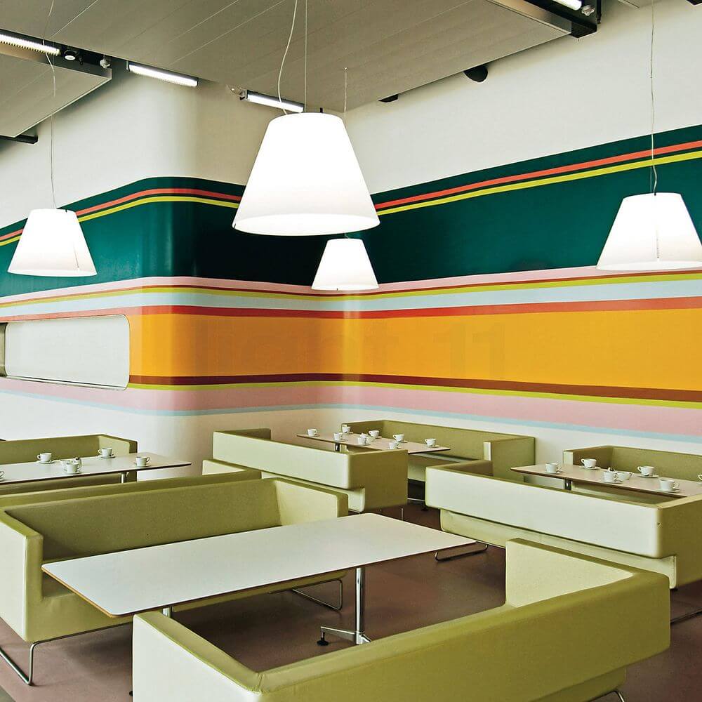 Luceplan Hängeleuchte Grande Costanza Ø 70cm in einem modernen Café mit bunten Wänden und stilvollen Sitzbereichen.