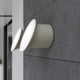 Luceplan LED Außen-Wandlampe Ecran IP65 an einer grauen Wand, sanftes Licht aus zylinderförmigem Design.