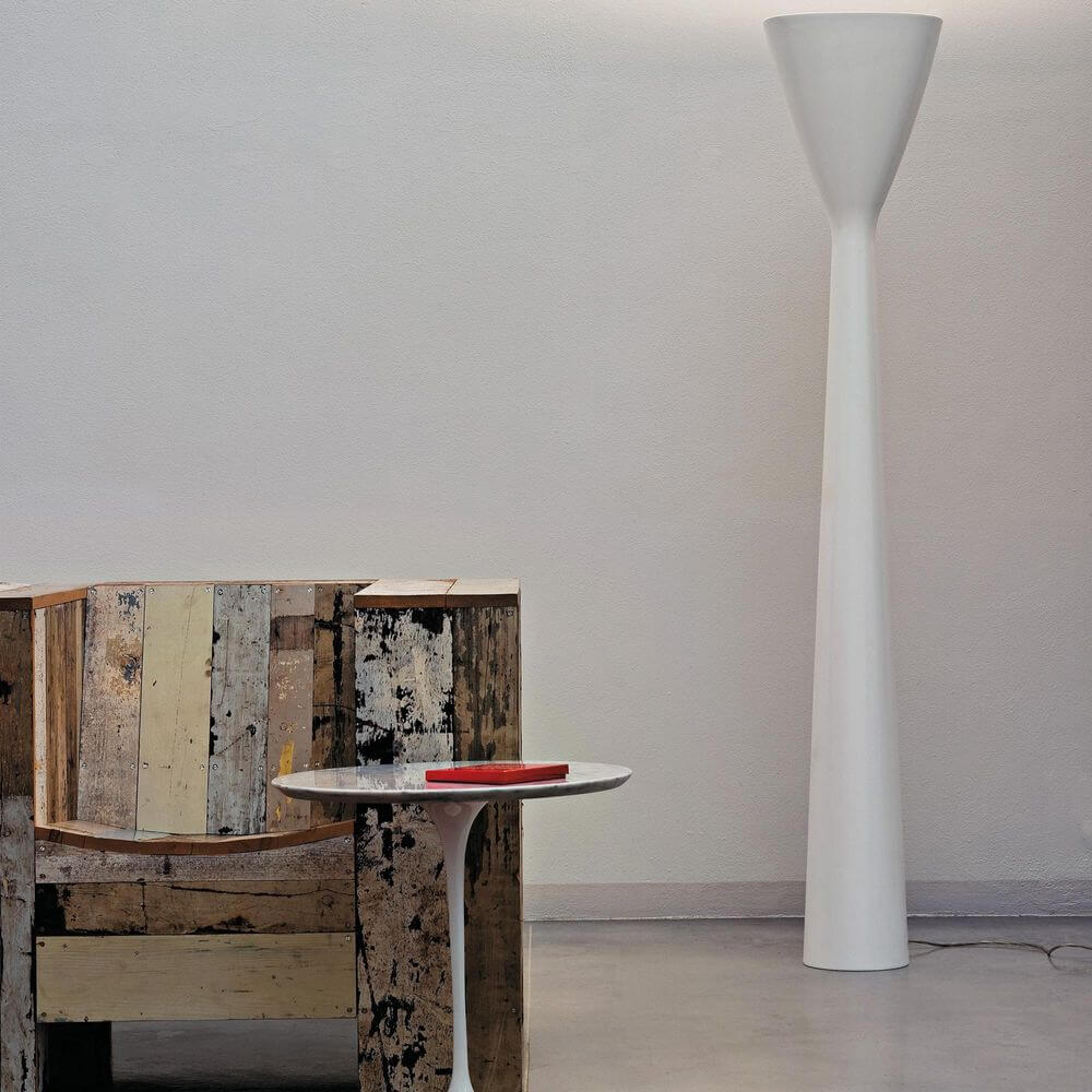 Luceplan LED Stehleuchte Carrara 185cm neben einem modernen Holzstuhl und einem minimalistischen Tisch.