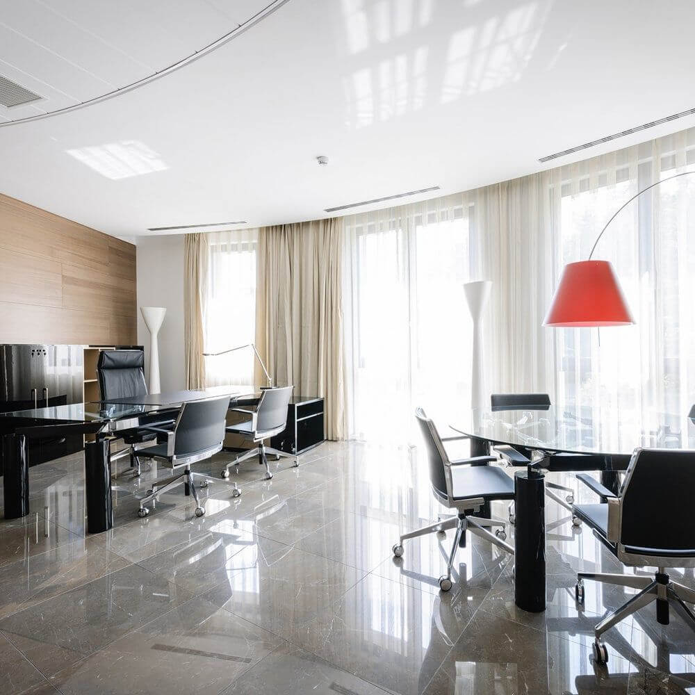 Moderne Büroumgebung mit Luceplan LED Stehleuchte Carrara 185cm, eleganten Stühlen und Fenstern mit viel Tageslicht.