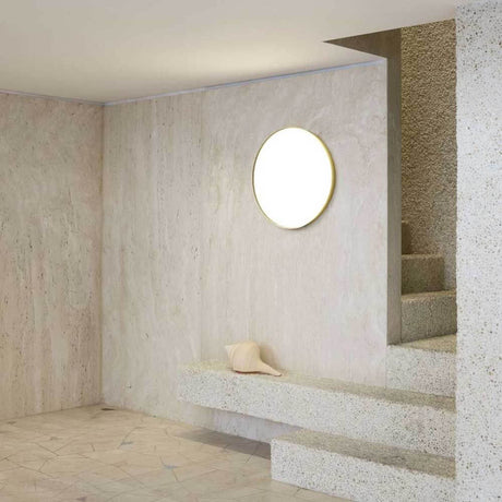 Luceplan LED Wand- & Deckenlampe Compendium Plate Ø 56cm, montiert an einer modernen Wand in einem stilvollen Raum.