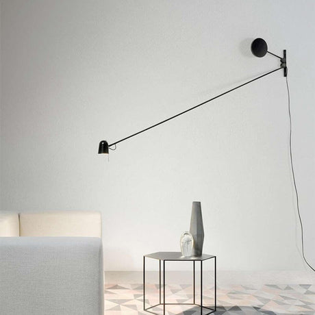 Luceplan LED applique murale Counterbalance avec contrepoids 190 cm placée sur un mur au-dessus d’une table.
