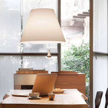 Luceplan Lady Costanza Hängelampe über einem Tisch in einem modernen Raum mit Fenster und Pflanzen.