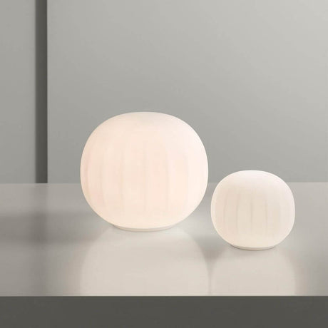 Luceplan Lita Tischlampe Ø 14cm Opal auf einem Tisch in minimalistischer Umgebung.