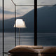 Luceplan Stehlampe Costanza mit Sensor-Dimmer vor einem modernen Fenster mit Bergblick.