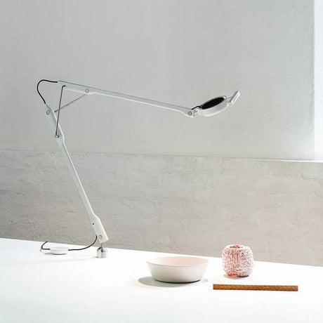 Luceplan Tivedo LED Büro-Tischlampe mit Präsenzsensor 3000K auf einem Tisch mit einer Schüssel und Dekoration.