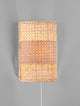 Lum Wandleuchte Natur aus Rattan mit warmem Licht an einer grauen Wand