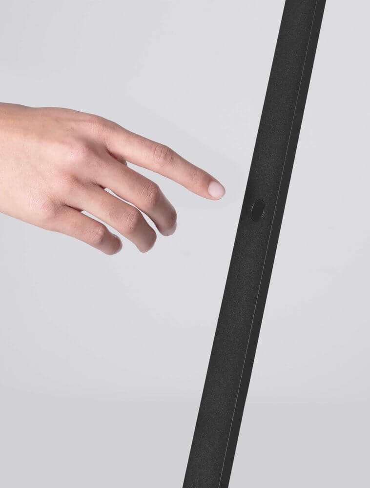 Hand, die die Lusa LED Stehlampe 3000K Champagner, Schwarz berührt, um das Licht zu steuern.
