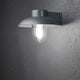 Mani Außen-Wandleuchte Silber, klares Glas an einer Wand montiert mit leuchtendem Glas.