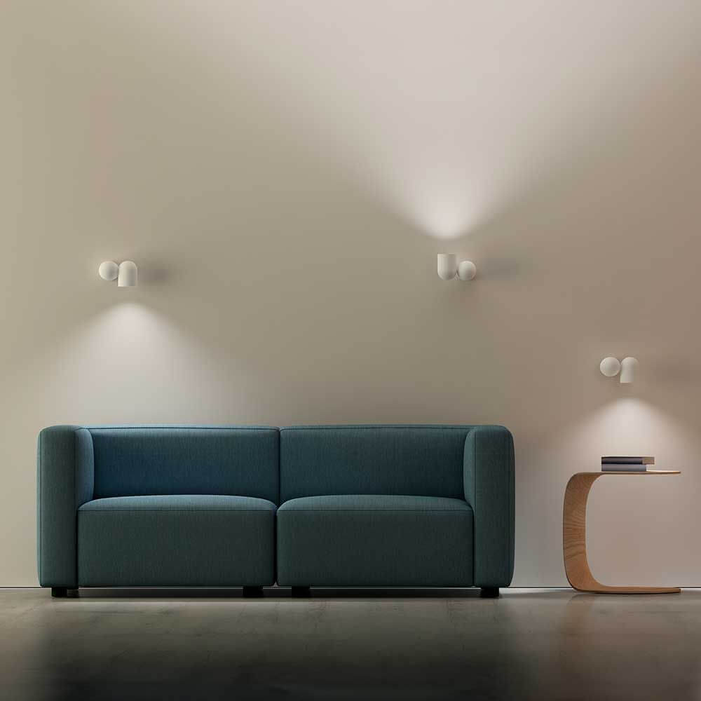 Moderne Innenansicht mit Ios Wandstrahlern über einem blauen Sofa und einem stilvollen Beistelltisch.