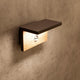 Ruka Sensor Außen-LED-Wandlampe Dunkelgrau an einer Wand, modern und robust mit Holz- und Metallkombination.