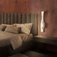 Sahara LED Wandleuchte über einem modern gestalteten Bett mit Kissen und Nachtisch.