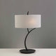 Tischlampe Eve in modernem Design mit runder Textilschirm und metallischem Gestell auf einem Tisch.