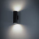 Moderne Volcano Wandleuchte Graphit mit runder Form und sanftem Lichtstrahl an der Wand.