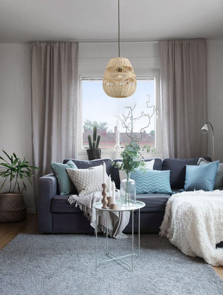 Marlo Pendelleuchte Birne Beige Rattan über einem modernen Sofa mit Kissen und Dekoration im Ethno-Stil.