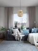 Marlo Pendelleuchte Birne Beige Rattan über einem modernen Sofa mit Kissen und Dekoration im Ethno-Stil.