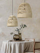 Marlo Pendelleuchte Glocke Beige Rattan über einem gedeckten Tisch mit Vase und Blumen.