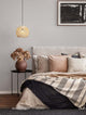 Marlo Pendelleuchte Kuppel Beige Rattan über einem eleganten Bett mit Kissen und einer dekorativen Vase.