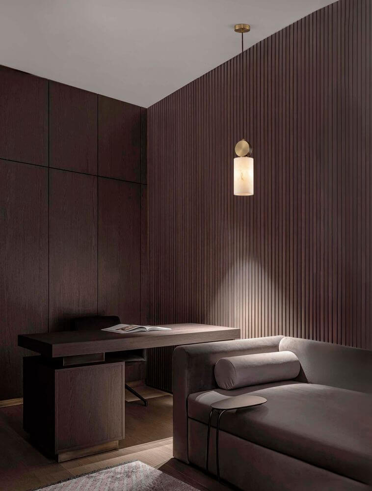 Maru Pendelleuchte Gold in modernem Wohnraum mit dunklem Holz und eleganter Einrichtung.