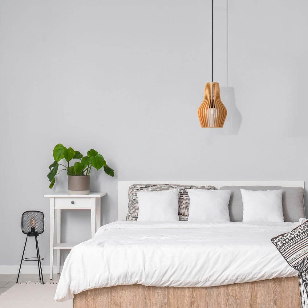 Holz Hängeleuchte Roots in Tropfenform über einem modernen Schlafzimmer mit Pflanzen und minimalistischer Einrichtung.