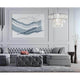 Puntes Pendelleuchte 18-flammig über einem modernen Wohnzimmer mit grauem Sofa und abstrakter Wandkunst.