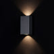 TimesSquare LED-Außenwandlampe Small IP54 an einer dunklen Wand mit sanfter Beleuchtung.