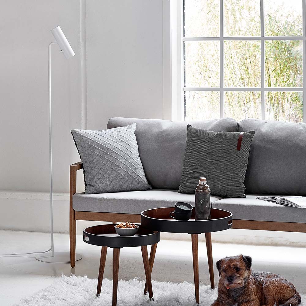 MIB 6 Stehleuchte in Weiß neben einem grauen Sofa, stilvolle Wohnungseinrichtung mit Hund.