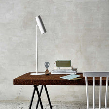 Lámpara de mesa Mib 6 blanca sobre una mesa con libros y objetos decorativos en un estilo escandinavo moderno.
