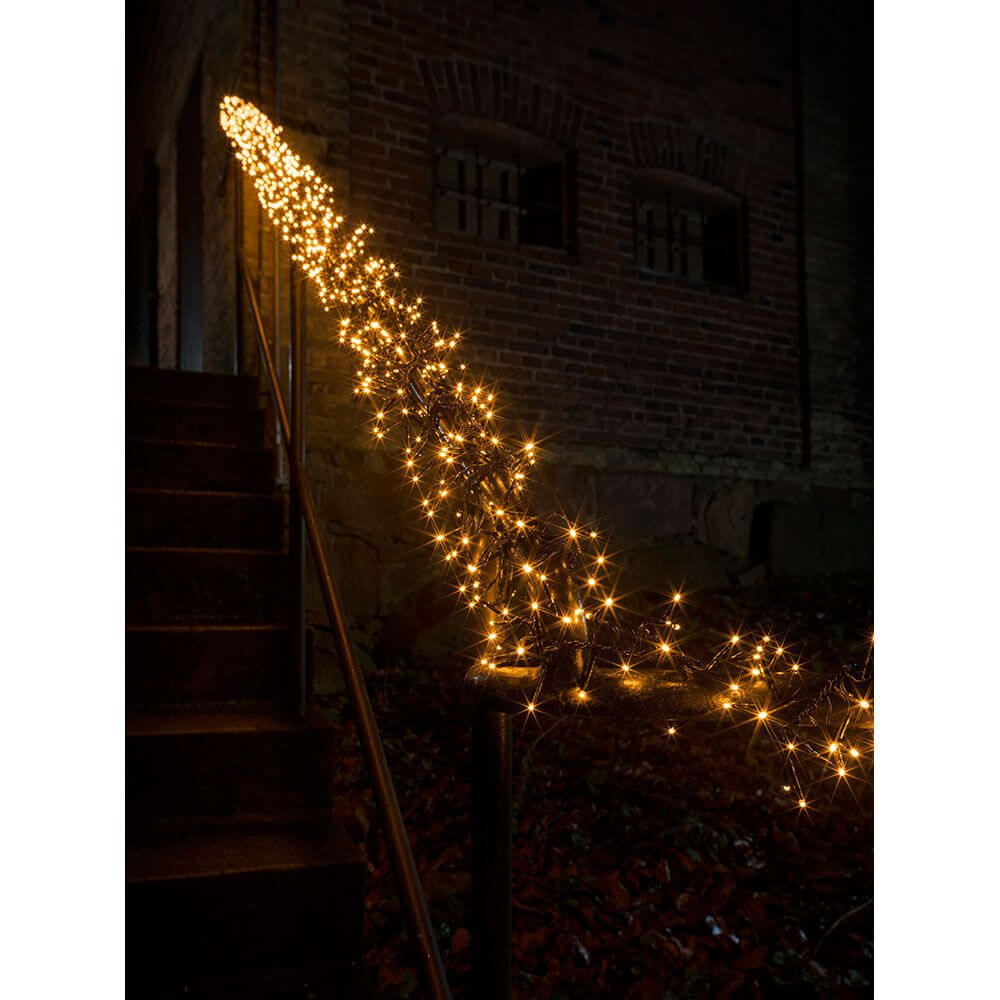 9m Micro LED Büschellichterkette Cluster mit 8 Funktionen 960 bernsteinfarbene Dioden IP44 an einem Treppengeländer im Dunkeln.