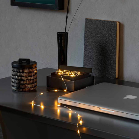 2,5 m mikro LED Eventyrlygter med USB-tilslutning 50 lyspunkter dekoreret på bordet i et stilfuldt boligmiljø.